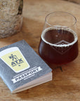 Passport-style beer tasting guide with a glass of dark beer on a wooden surface