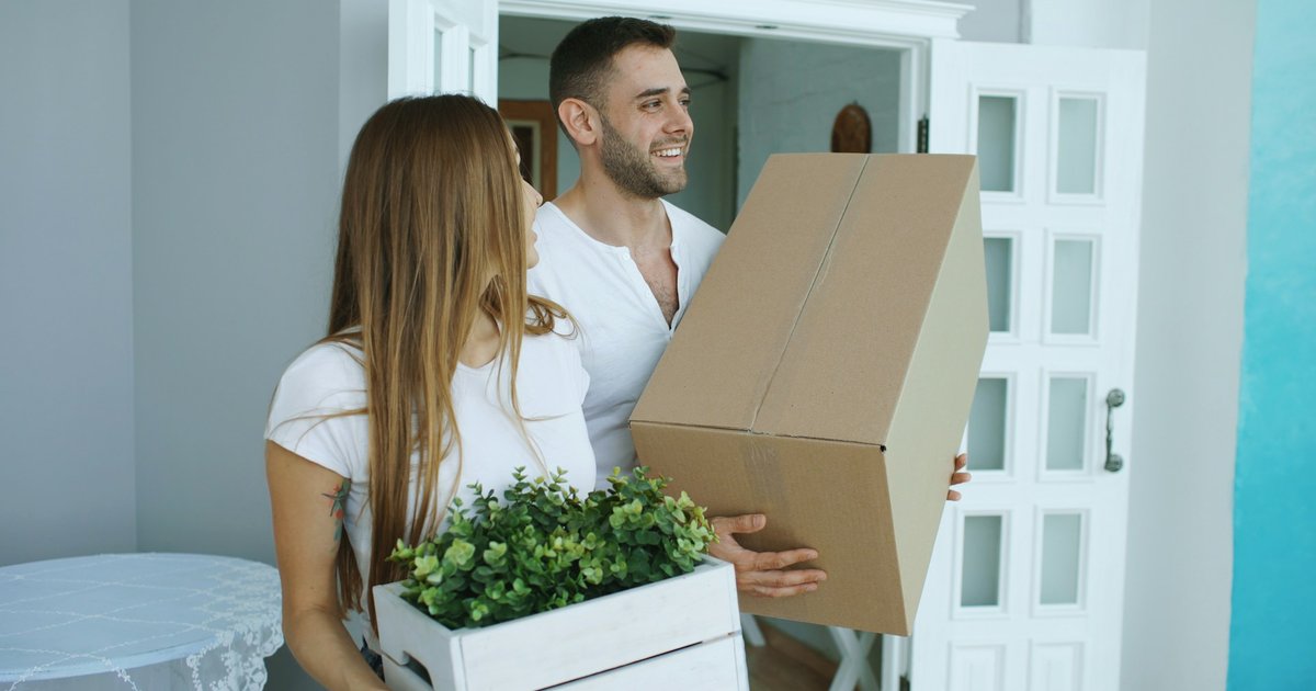 Couple carrying moving boxes into a new home in Austin, Texas