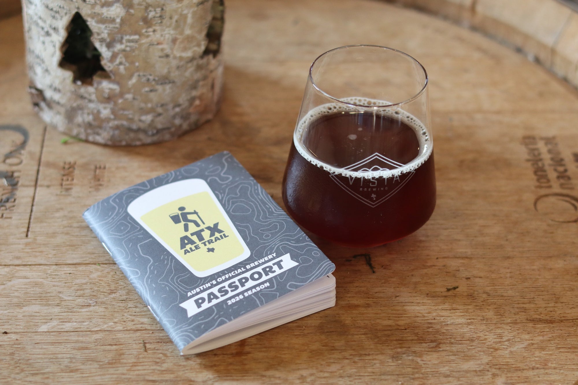 Passport-style beer tasting guide with a glass of dark beer on a wooden surface